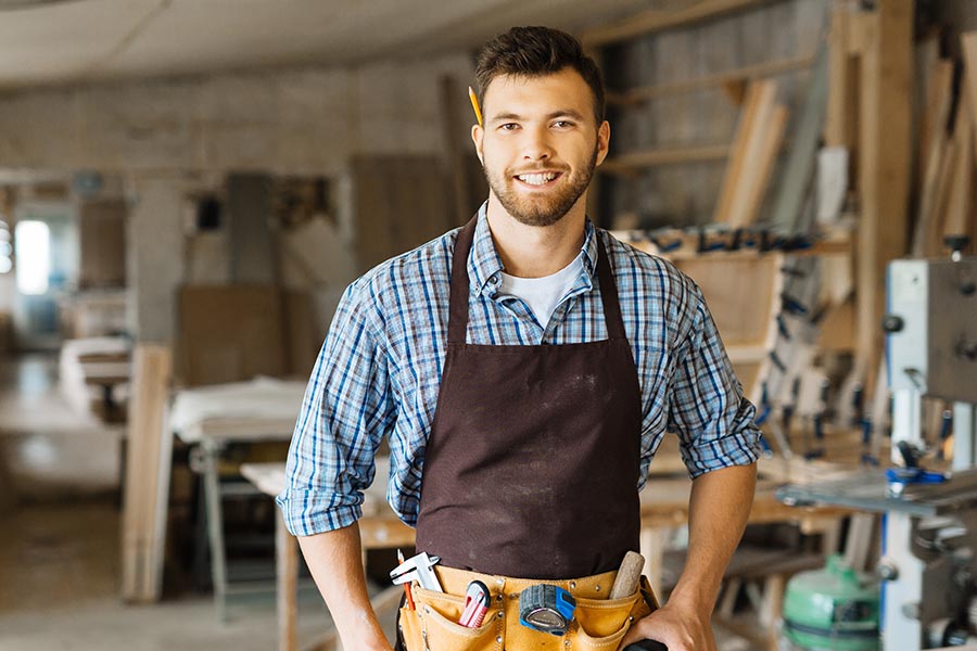 Specialized Business Insurance - Young Carpenter Stands Inside a Job Site Wearing Tool Belt and Apron